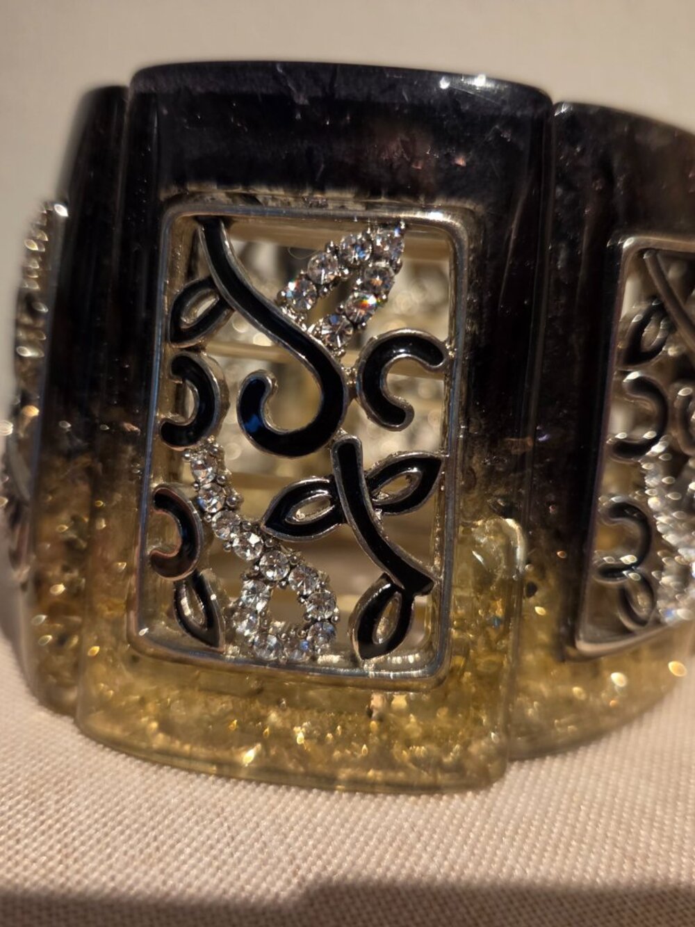 Elastic-band bangle with an inlaid design and embellishments.